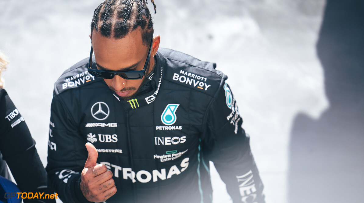 Hamilton poseert met zijn al zijn Mercedes-helmen